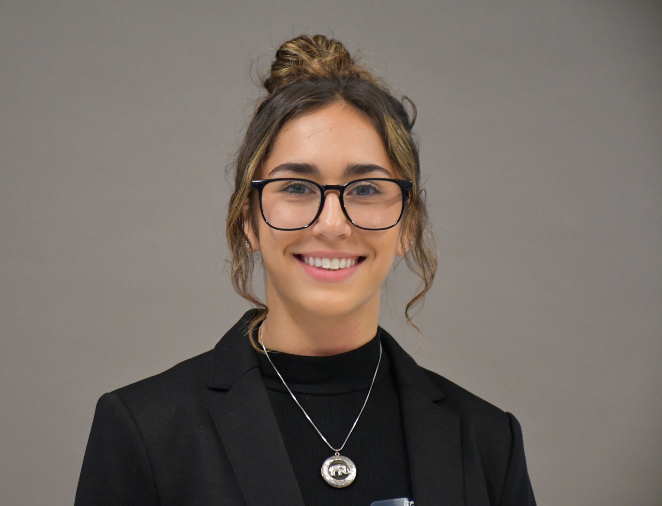 Portrait of Payton Brenner, wearing a black blazer and glasses